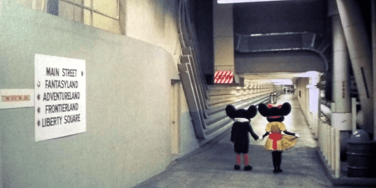 Foto traseira de Mickey e Minnie andando por um corredor do Utilidor sob o Magic Kingdom Park
