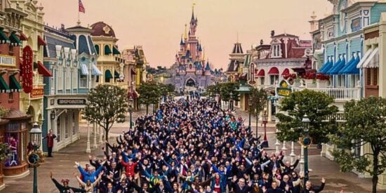 Uma grande multidão com as mãos para cima dentro da Disneyland Paris