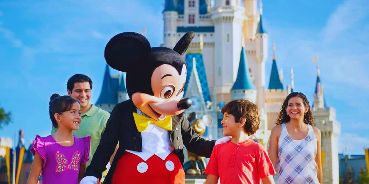 Mickey Mouse em frente ao Castelo da Cinderela dentro do Magic Kingdom com um casal de crianças