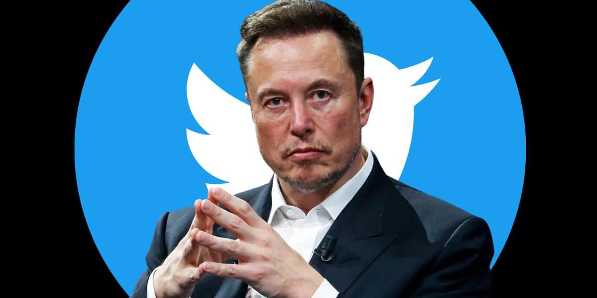 Elon Musk junta as mãos como se estivesse tramando na frente do antigo logotipo do Twitter